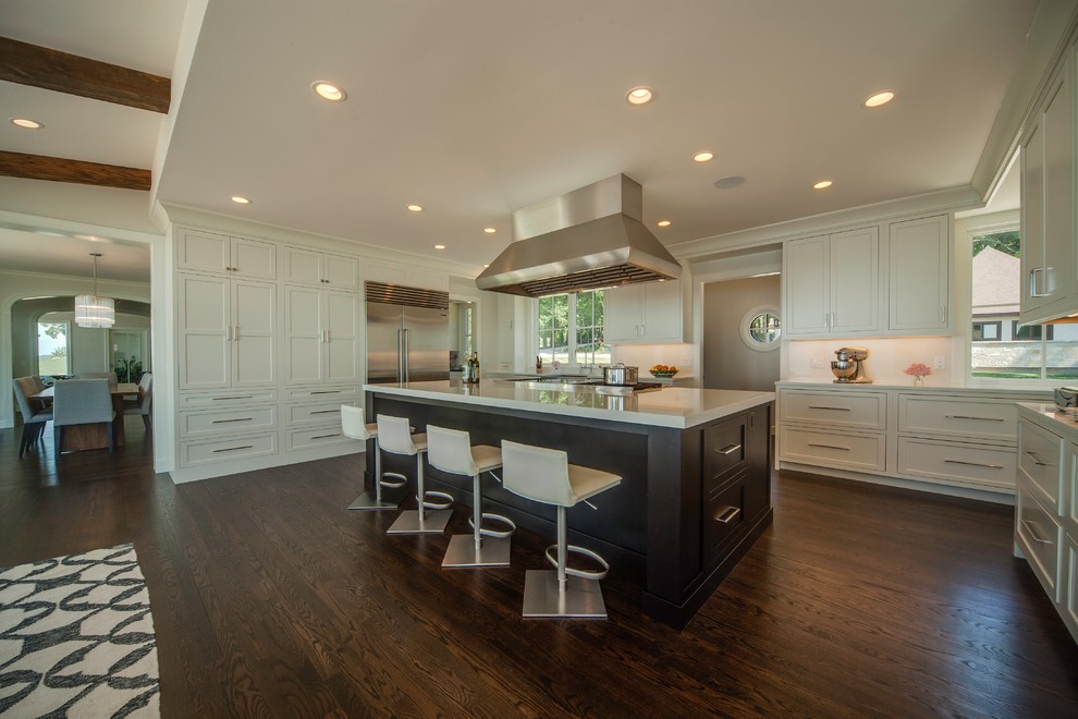 Exemple d'une grande cuisine moderne avec un placard à porte shaker, un plan de travail en quartz modifié, une crédence blanche, un électroménager en acier inoxydable, un sol en bois brun, îlot et un plan de travail gris.