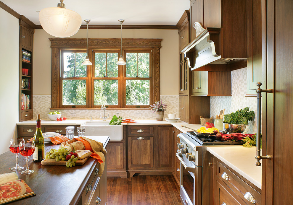 Arts and crafts kitchen photo in Huntington with wood countertops, a farmhouse sink, dark wood cabinets, beige backsplash, shaker cabinets and stainless steel appliances