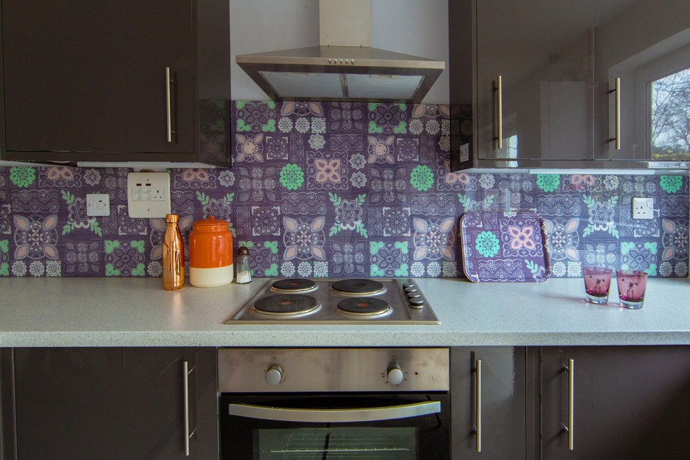 Foto på ett mellanstort eklektiskt kök och matrum, med släta luckor, grå skåp, laminatbänkskiva, flerfärgad stänkskydd, glaspanel som stänkskydd och rostfria vitvaror