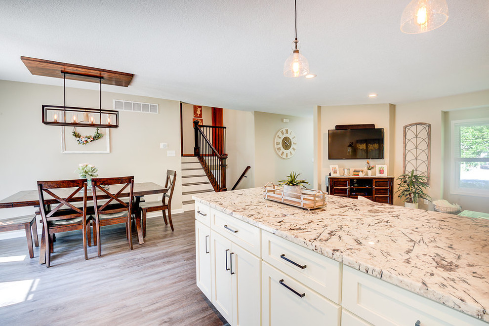Example of a mid-sized country u-shaped vinyl floor and brown floor eat-in kitchen design in Minneapolis with a farmhouse sink, shaker cabinets, white cabinets, granite countertops, gray backsplash, glass tile backsplash, stainless steel appliances, a peninsula and white countertops