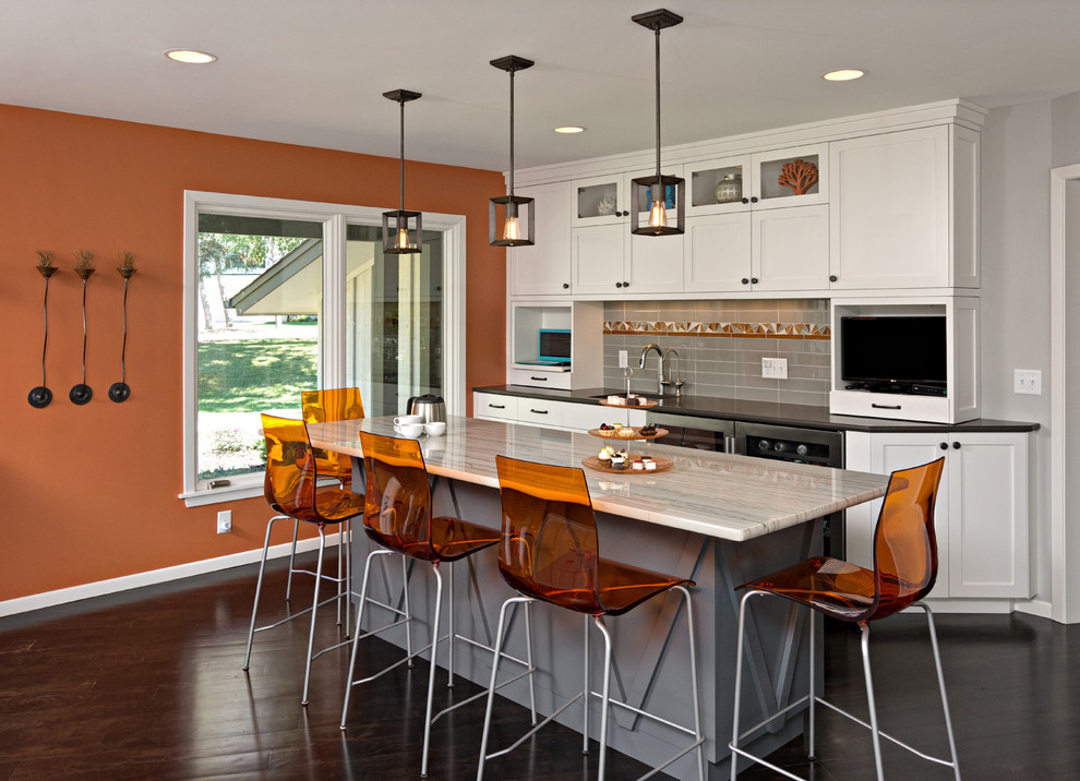 Expansive retro l-shaped kitchen/diner in Minneapolis with a single-bowl sink, recessed-panel cabinets, white cabinets, engineered stone countertops, grey splashback, glass tiled splashback, stainless steel appliances, dark hardwood flooring, an island, black floors and grey worktops.