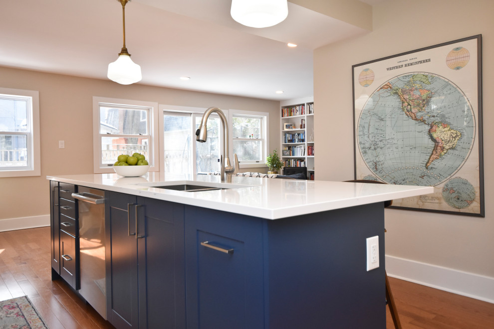 This is an example of a medium sized contemporary kitchen/diner in Ottawa with a submerged sink, shaker cabinets, blue cabinets, engineered stone countertops, porcelain splashback, stainless steel appliances, light hardwood flooring, an island and white worktops.