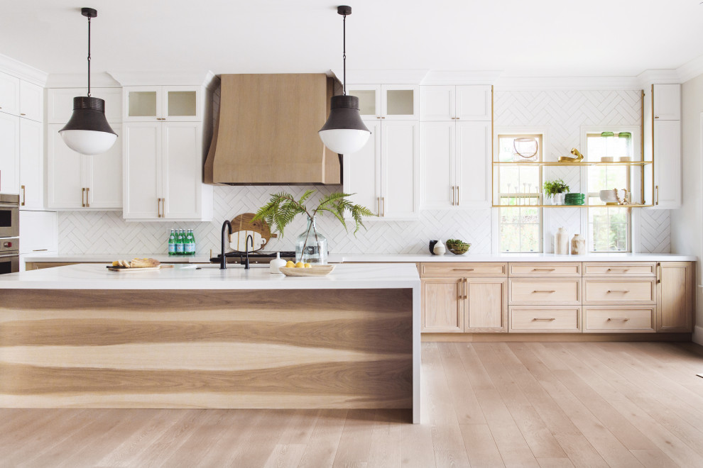 Transitional l-shaped medium tone wood floor and brown floor open concept kitchen photo in San Diego with an undermount sink, recessed-panel cabinets, light wood cabinets, white backsplash, stainless steel appliances, an island and white countertops