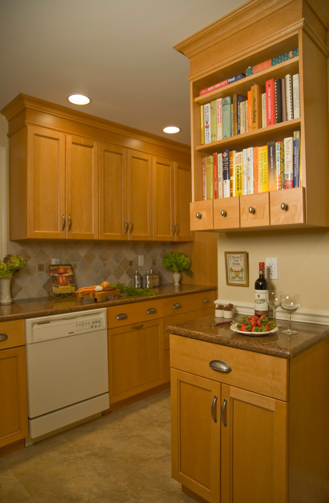 Inredning av ett litet kök, med en undermonterad diskho, luckor med infälld panel, skåp i ljust trä, granitbänkskiva, flerfärgad stänkskydd, stänkskydd i keramik, vita vitvaror och linoleumgolv