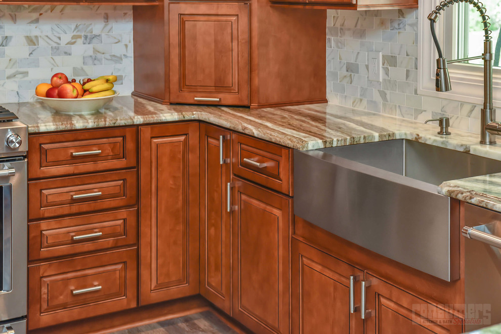 Idéer för mellanstora flerfärgat kök, med en rustik diskho, luckor med upphöjd panel, bruna skåp, granitbänkskiva, vitt stänkskydd, rostfria vitvaror och en halv köksö