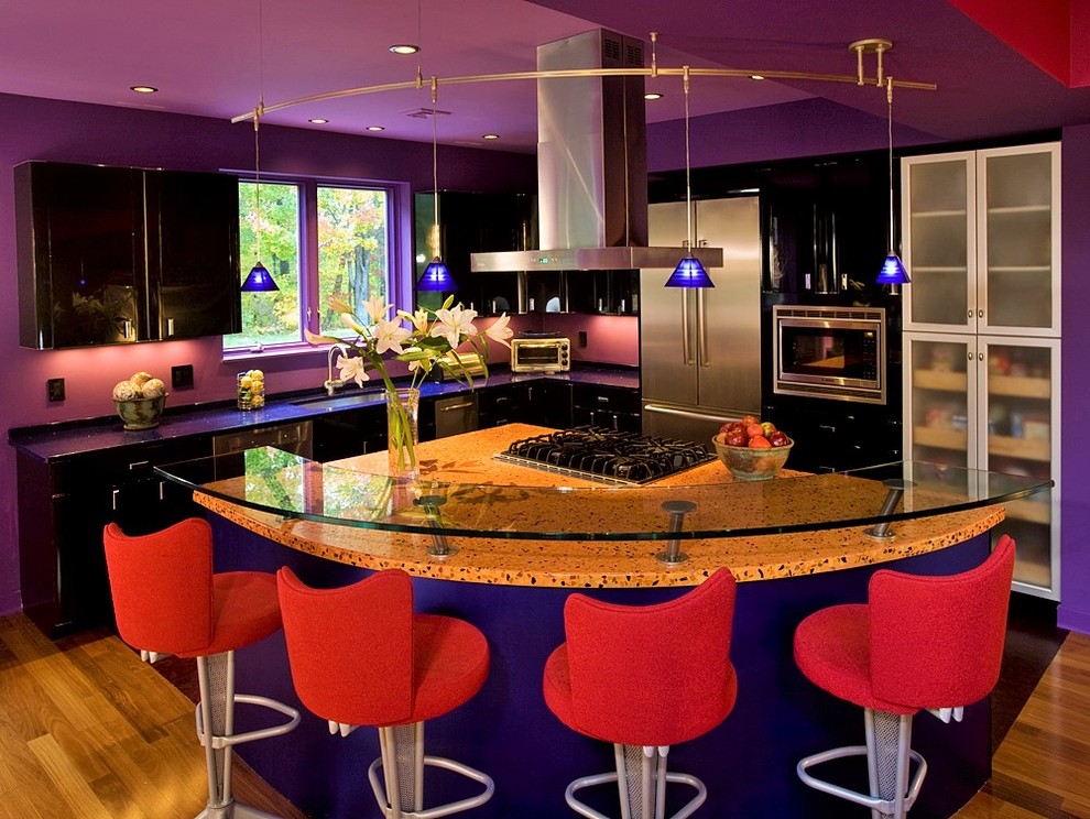 Immagine di una cucina eclettica di medie dimensioni con ante lisce, ante nere, elettrodomestici in acciaio inossidabile e pavimento in legno massello medio