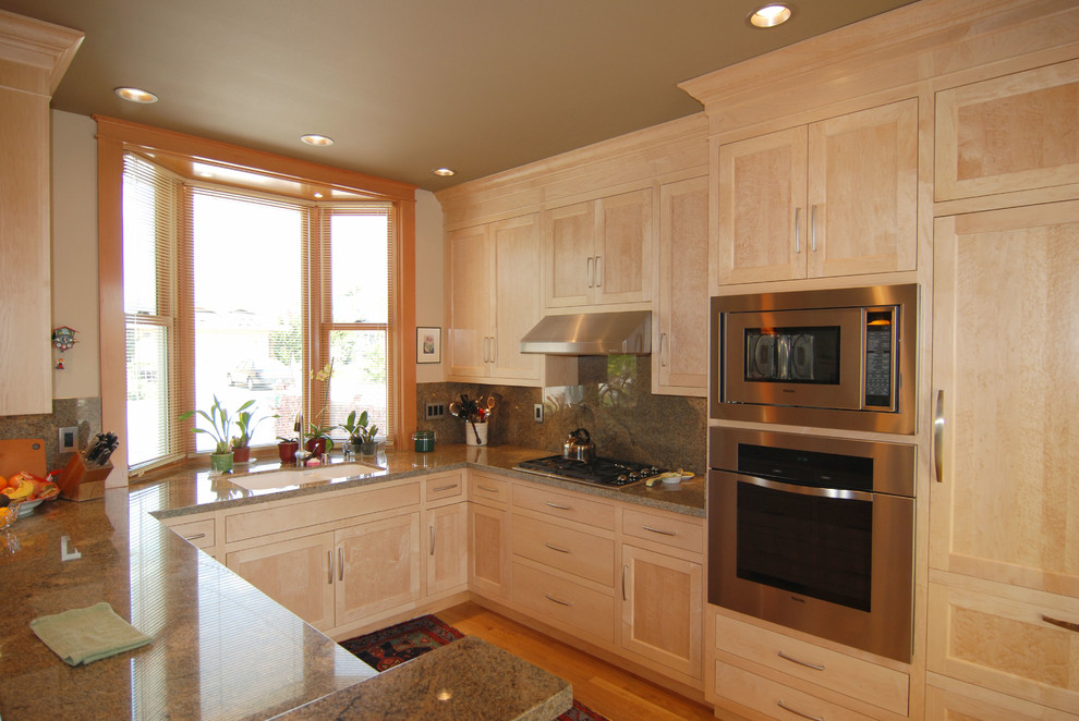 Example of a mid-sized classic u-shaped medium tone wood floor eat-in kitchen design in San Francisco with a double-bowl sink, shaker cabinets, light wood cabinets, granite countertops, gray backsplash, stone slab backsplash, stainless steel appliances and a peninsula