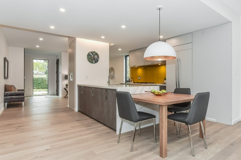 Inspiration for a large modern single-wall open plan kitchen in Toronto with a submerged sink, flat-panel cabinets, white cabinets, quartz worktops, yellow splashback, integrated appliances, light hardwood flooring, an island, beige floors and white worktops.