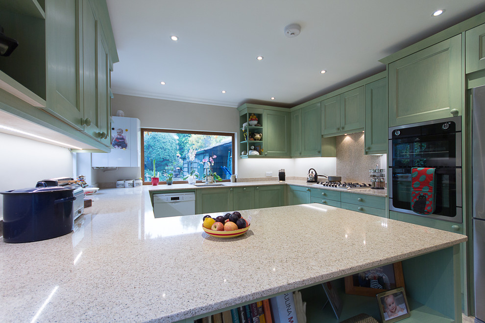 This is an example of a large farmhouse u-shaped kitchen/diner in London with an integrated sink, shaker cabinets, medium wood cabinets, composite countertops, beige splashback, stone slab splashback, stainless steel appliances, porcelain flooring and no island.