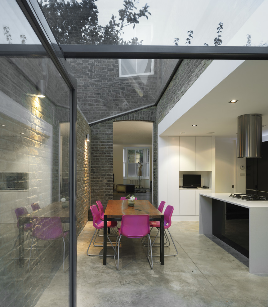 Modern inredning av ett kök och matrum, med släta luckor, vita skåp, betonggolv och en köksö