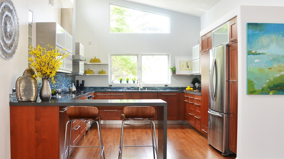 Foto på ett mellanstort funkis kök, med skåp i shakerstil, skåp i mellenmörkt trä, stänkskydd med metallisk yta, stänkskydd i mosaik, rostfria vitvaror, mellanmörkt trägolv och en halv köksö