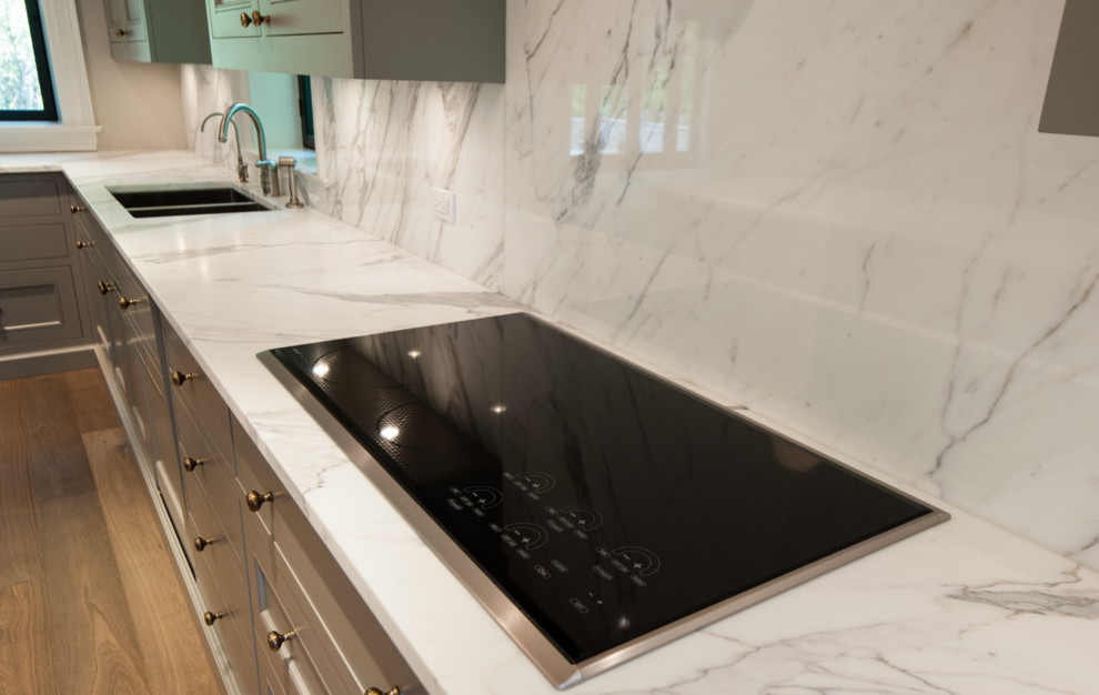 Inspiration for a large contemporary l-shaped medium tone wood floor eat-in kitchen remodel in Toronto with an undermount sink, recessed-panel cabinets, gray cabinets, marble countertops, white backsplash, stone slab backsplash, stainless steel appliances and an island