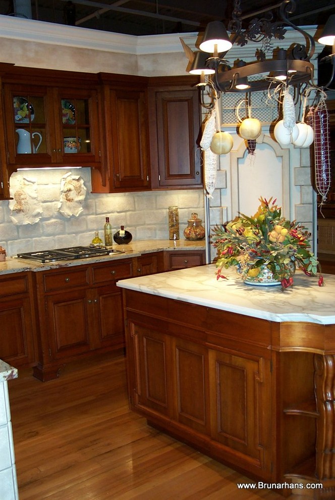 Example of a mid-sized classic l-shaped medium tone wood floor kitchen design in Bridgeport with raised-panel cabinets, medium tone wood cabinets, marble countertops, white backsplash, stone tile backsplash, an island and stainless steel appliances