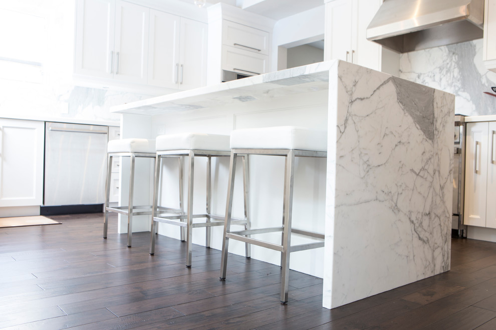 Bild på ett mellanstort vintage kök och matrum, med en dubbel diskho, luckor med infälld panel, vita skåp, marmorbänkskiva, vitt stänkskydd, stänkskydd i sten, vita vitvaror, mörkt trägolv och en köksö