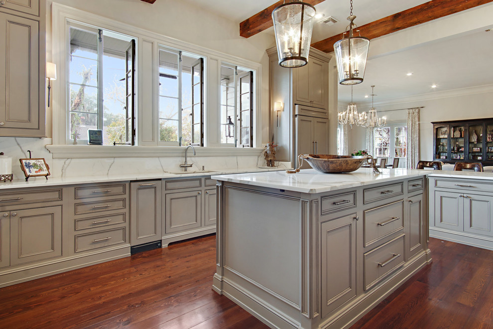 Inspiration for a large traditional u-shaped enclosed kitchen in New Orleans with a submerged sink, shaker cabinets, beige cabinets, marble worktops, marble splashback, stainless steel appliances, dark hardwood flooring, an island and brown floors.