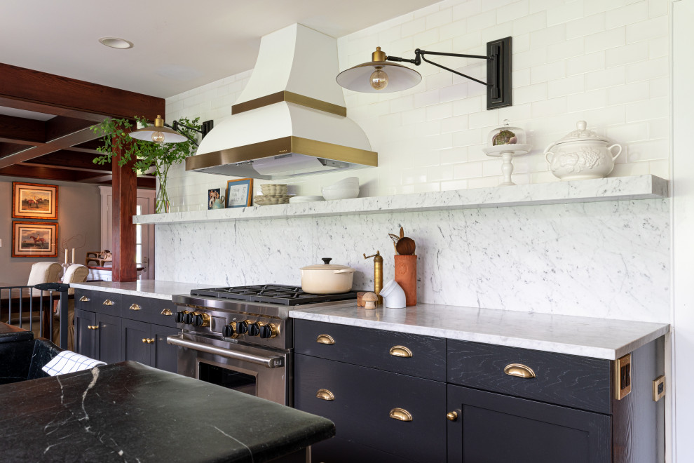 Photo of a medium sized traditional u-shaped kitchen/diner in Philadelphia with a triple-bowl sink, flat-panel cabinets, black cabinets, marble worktops, white splashback, marble splashback, stainless steel appliances, ceramic flooring, an island, beige floors and white worktops.