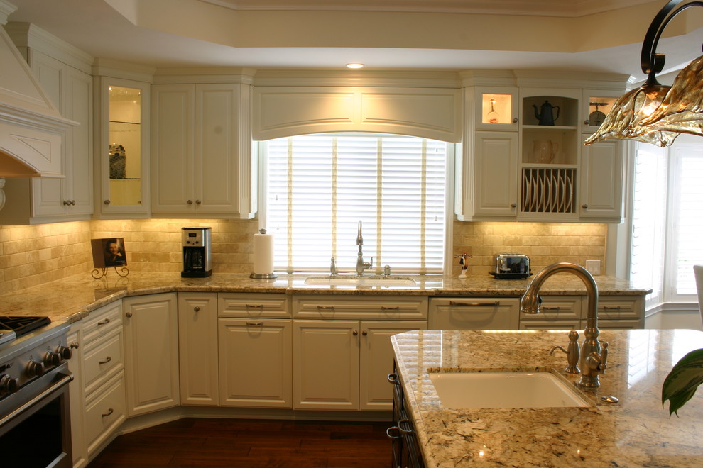 Bild på ett stort vintage u-kök, med en undermonterad diskho, luckor med upphöjd panel, vita skåp, marmorbänkskiva, beige stänkskydd, stänkskydd i stenkakel, integrerade vitvaror, mörkt trägolv och en köksö