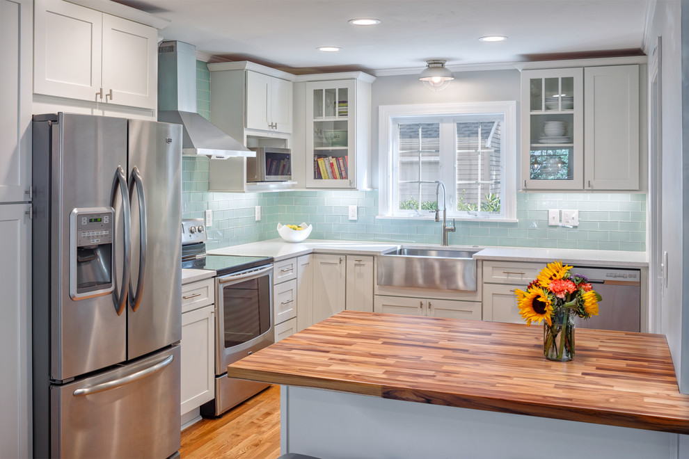Eat-in kitchen - mid-sized coastal l-shaped light wood floor eat-in kitchen idea in Boston with a farmhouse sink, shaker cabinets, white cabinets, quartzite countertops, blue backsplash, glass tile backsplash, stainless steel appliances and an island