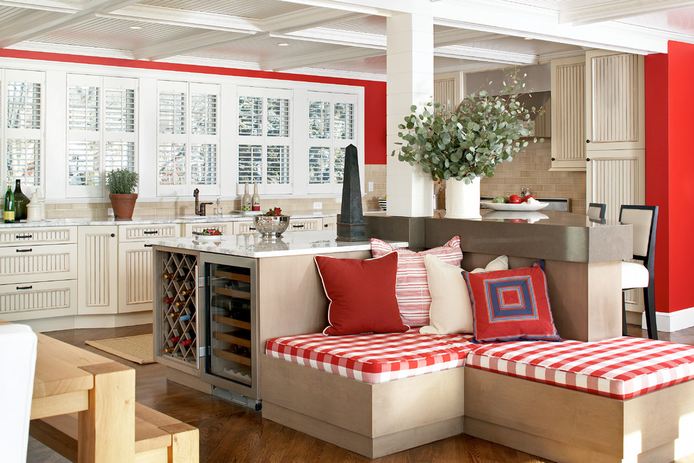 Example of a large beach style l-shaped medium tone wood floor eat-in kitchen design in Boston with recessed-panel cabinets, beige cabinets, beige backsplash, subway tile backsplash, marble countertops, an island, an undermount sink and stainless steel appliances