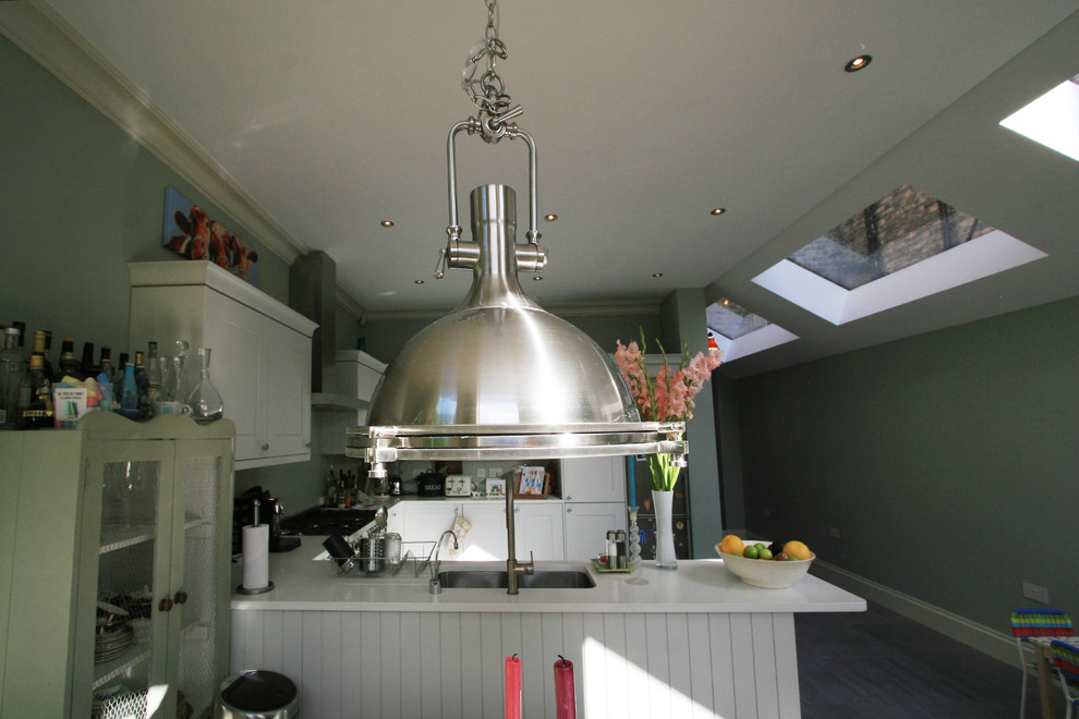 Medium sized traditional u-shaped kitchen/diner in London with a submerged sink, shaker cabinets, white cabinets, granite worktops, stainless steel appliances, porcelain flooring and no island.