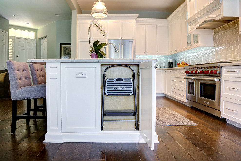 Klassisk inredning av ett mellanstort kök, med en undermonterad diskho, skåp i shakerstil, vita skåp, bänkskiva i kvartsit, grått stänkskydd, stänkskydd i tunnelbanekakel, rostfria vitvaror och en köksö