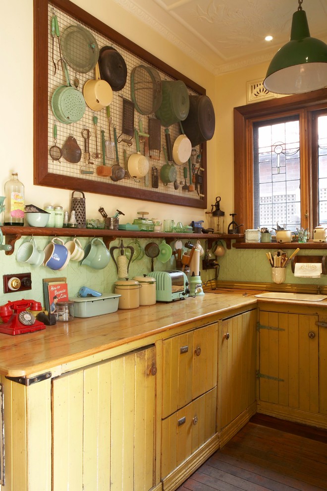 Idee per una cucina a L country con lavello da incasso, ante gialle, top in legno, paraspruzzi verde e pavimento in legno massello medio