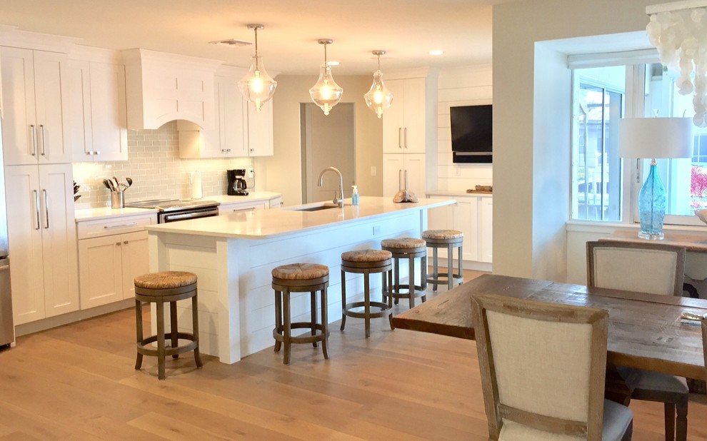 Mid-sized beach style l-shaped light wood floor eat-in kitchen photo in Tampa with a single-bowl sink, shaker cabinets, white cabinets, quartz countertops, blue backsplash, ceramic backsplash, stainless steel appliances and an island