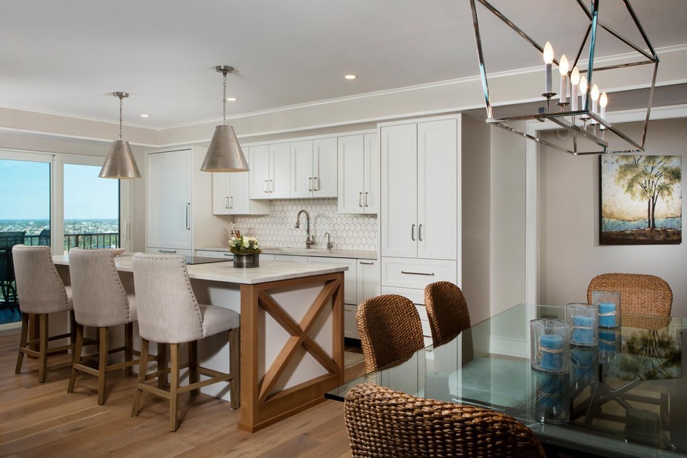 Example of a mid-sized trendy single-wall medium tone wood floor and brown floor open concept kitchen design in Other with recessed-panel cabinets, white cabinets, an island, an undermount sink, paneled appliances, white backsplash, ceramic backsplash and white countertops