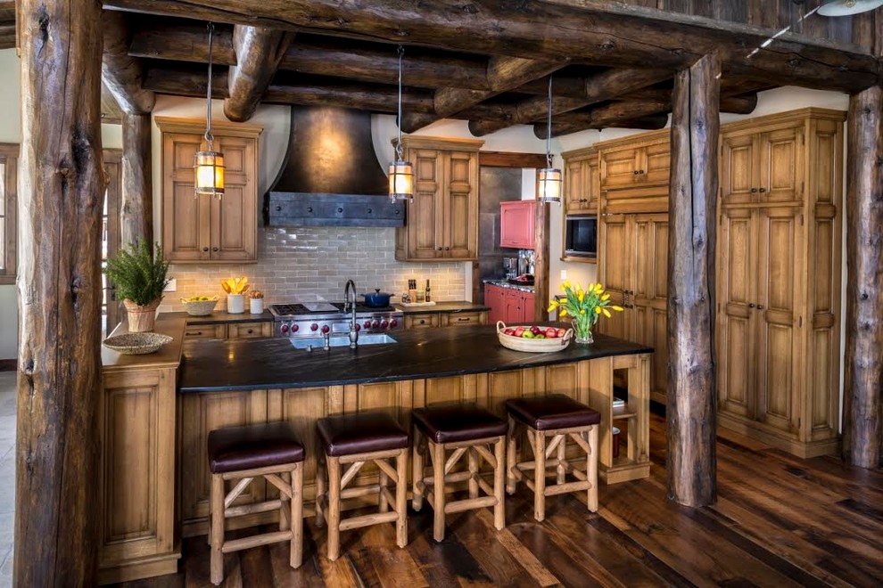 Example of a large mountain style u-shaped dark wood floor eat-in kitchen design in Denver with an undermount sink, raised-panel cabinets, medium tone wood cabinets, soapstone countertops, beige backsplash, subway tile backsplash and stainless steel appliances