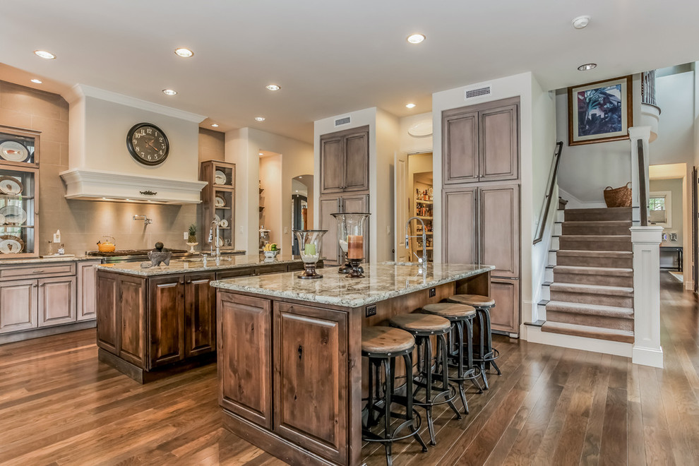 Inspiration for a classic kitchen in Austin with a submerged sink, raised-panel cabinets, medium wood cabinets, grey splashback, dark hardwood flooring, multiple islands and brown floors.