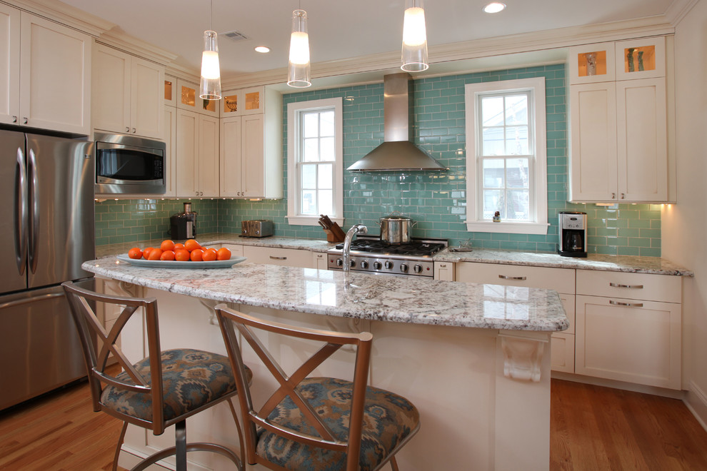 Inspiration for a mid-sized coastal l-shaped light wood floor open concept kitchen remodel in Philadelphia with a triple-bowl sink, shaker cabinets, white cabinets, granite countertops, green backsplash, glass tile backsplash, stainless steel appliances and an island