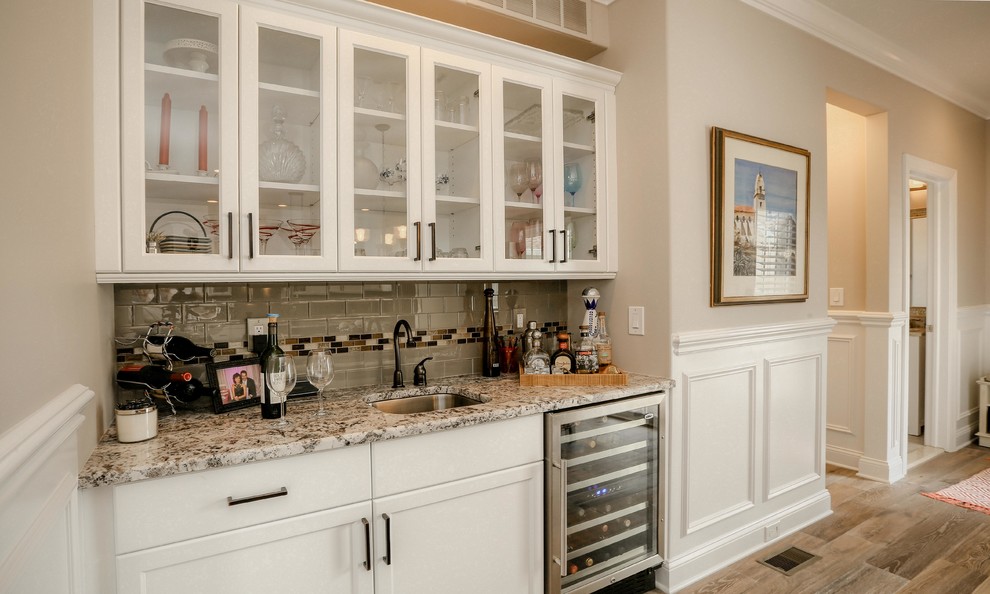 Mid-sized elegant single-wall kitchen photo in Philadelphia with stainless steel appliances, an undermount sink, glass-front cabinets, white cabinets and subway tile backsplash