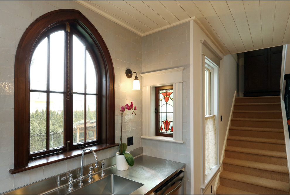 Small ornate single-wall medium tone wood floor open concept kitchen photo in Portland with an integrated sink, shaker cabinets, white cabinets, stainless steel countertops, gray backsplash, ceramic backsplash and stainless steel appliances
