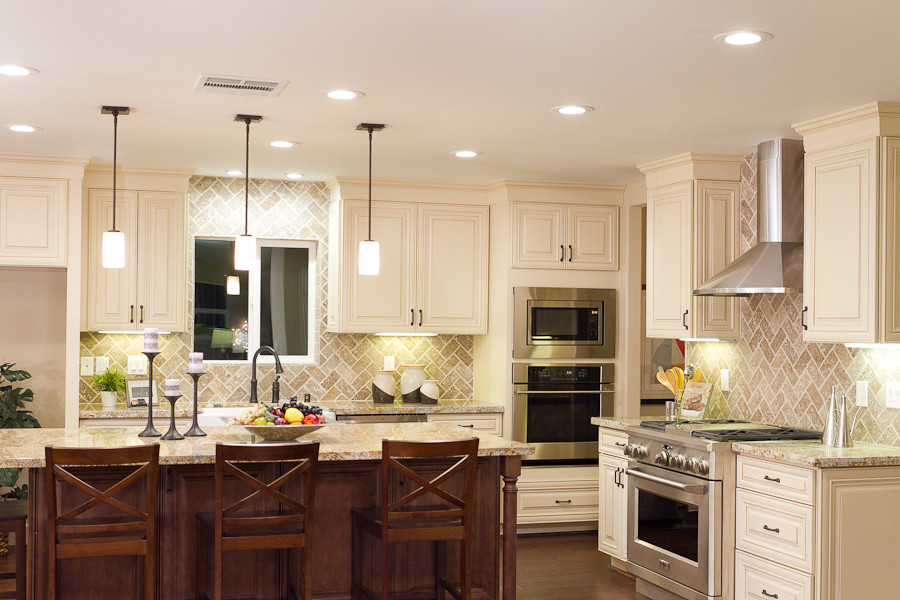 Kitchen - mid-sized traditional l-shaped dark wood floor kitchen idea in Sacramento with raised-panel cabinets, beige cabinets, granite countertops, beige backsplash, brick backsplash, stainless steel appliances and an island