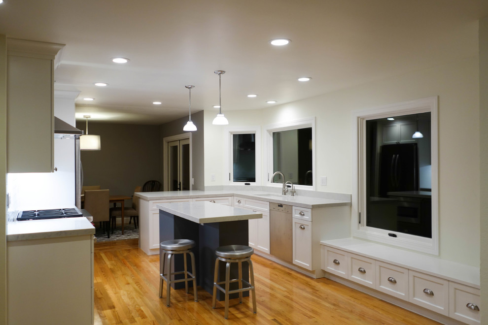 Idéer för ett mellanstort klassiskt vit kök, med en undermonterad diskho, luckor med infälld panel, vita skåp, bänkskiva i kvarts, vitt stänkskydd, stänkskydd i glaskakel, rostfria vitvaror, mellanmörkt trägolv, en köksö och orange golv