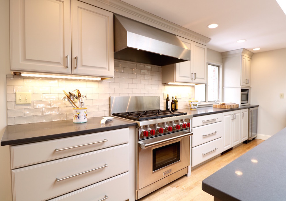 Large urban single-wall light wood floor eat-in kitchen photo in Boston with a double-bowl sink, raised-panel cabinets, gray cabinets, quartzite countertops, gray backsplash, ceramic backsplash, stainless steel appliances and an island