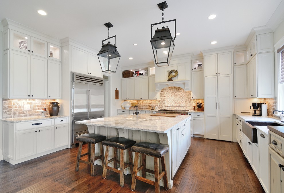 Large country u-shaped dark wood floor enclosed kitchen photo in Atlanta with a farmhouse sink, recessed-panel cabinets, white cabinets, stainless steel appliances, an island, quartz countertops, multicolored backsplash and stone tile backsplash