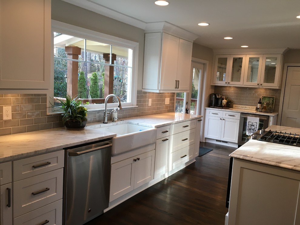 Inspiration for a medium sized traditional l-shaped kitchen in Atlanta with a belfast sink, shaker cabinets, white cabinets, stainless steel appliances, dark hardwood flooring, an island, brown floors, white worktops, grey splashback and metro tiled splashback.