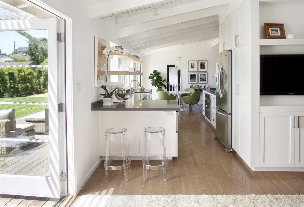 Foto de cocinas en U actual con armarios estilo shaker, electrodomésticos de acero inoxidable, puertas de armario blancas y fregadero sobremueble