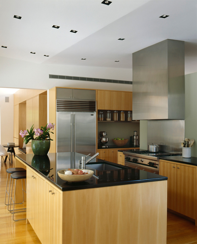 Inspiration for a contemporary kitchen in San Francisco with stainless steel appliances, light wood cabinets, flat-panel cabinets, a submerged sink, metallic splashback and metal splashback.