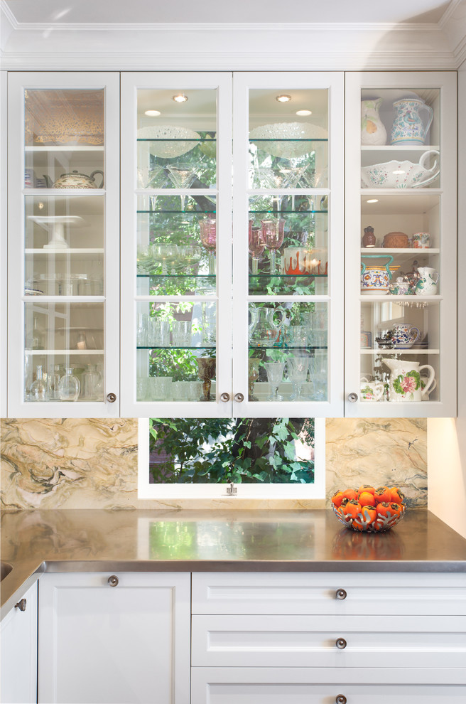 Foto på ett mellanstort vintage kök, med en undermonterad diskho, luckor med glaspanel, vita skåp, marmorbänkskiva, flerfärgad stänkskydd, stänkskydd i marmor, rostfria vitvaror, mellanmörkt trägolv och en köksö