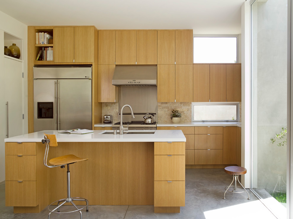 Inspiration for a mid-sized modern l-shaped concrete floor and gray floor open concept kitchen remodel in Los Angeles with an undermount sink, flat-panel cabinets, medium tone wood cabinets, quartz countertops, stone tile backsplash, stainless steel appliances, an island and beige backsplash