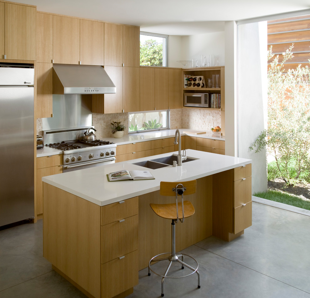 Immagine di una cucina moderna di medie dimensioni con lavello a doppia vasca, ante lisce, ante in legno chiaro, top in quarzite, paraspruzzi beige, elettrodomestici in acciaio inossidabile, pavimento in cemento, pavimento grigio e paraspruzzi con piastrelle in pietra