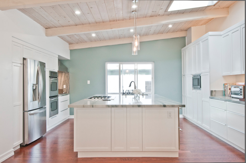 Idéer för att renovera ett stort maritimt grå grått kök, med en dubbel diskho, luckor med infälld panel, vita skåp, marmorbänkskiva, stänkskydd i sten, rostfria vitvaror, mellanmörkt trägolv, en köksö och brunt golv
