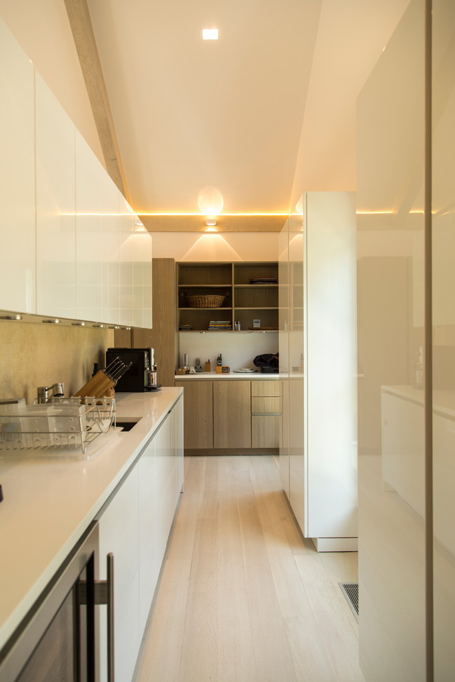 Geschlossene, Einzeilige Moderne Küche mit flächenbündigen Schrankfronten, weißen Schränken und hellem Holzboden in New York