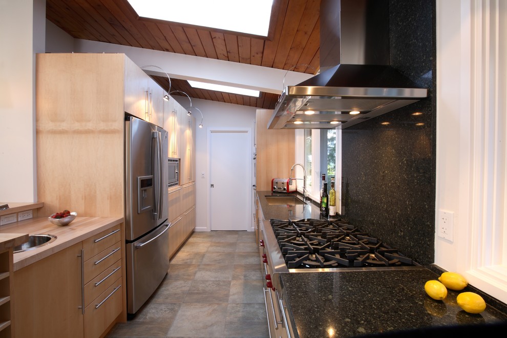 Trendy galley eat-in kitchen photo in Vancouver with an undermount sink, flat-panel cabinets, light wood cabinets, granite countertops, black backsplash, stone slab backsplash and stainless steel appliances