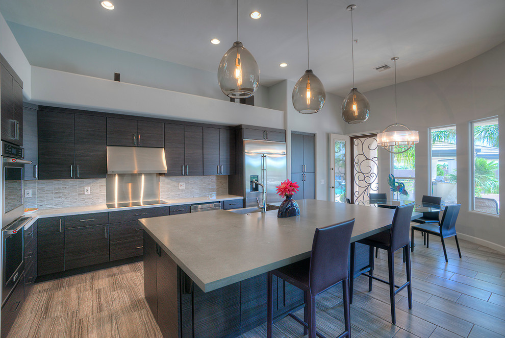 Inspiration for a mid-sized modern l-shaped eat-in kitchen remodel in Phoenix with flat-panel cabinets, dark wood cabinets, gray backsplash, stainless steel appliances and an island