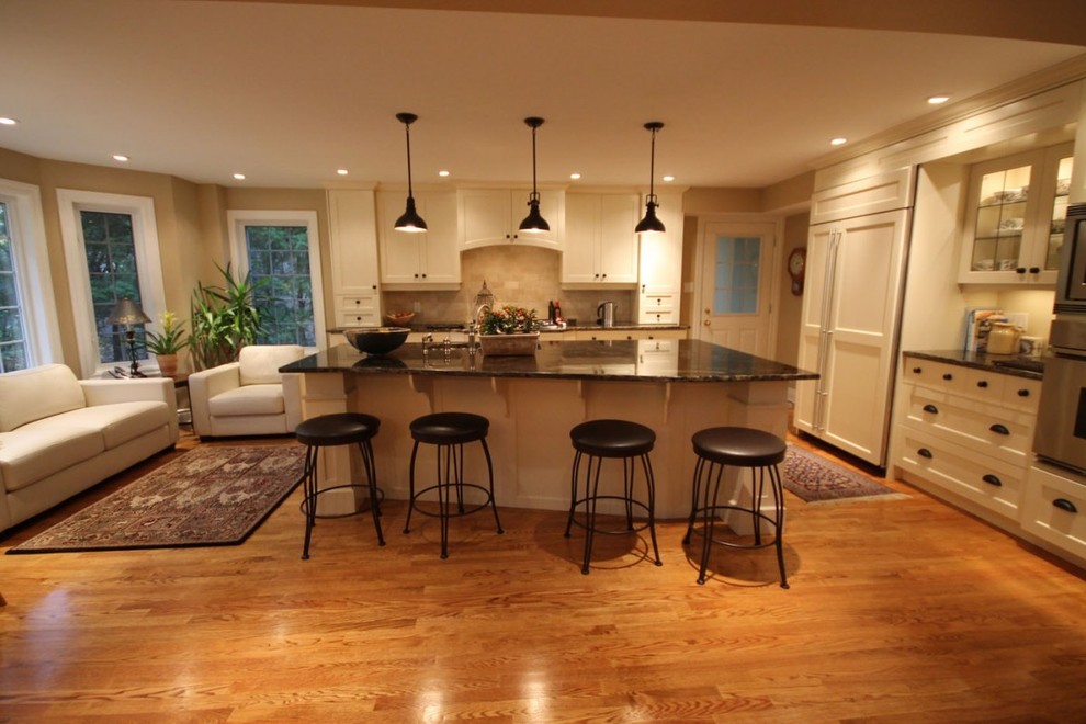 Idéer för ett stort klassiskt kök, med en dubbel diskho, luckor med infälld panel, vita skåp, granitbänkskiva, rostfria vitvaror, mellanmörkt trägolv, en köksö och brunt golv