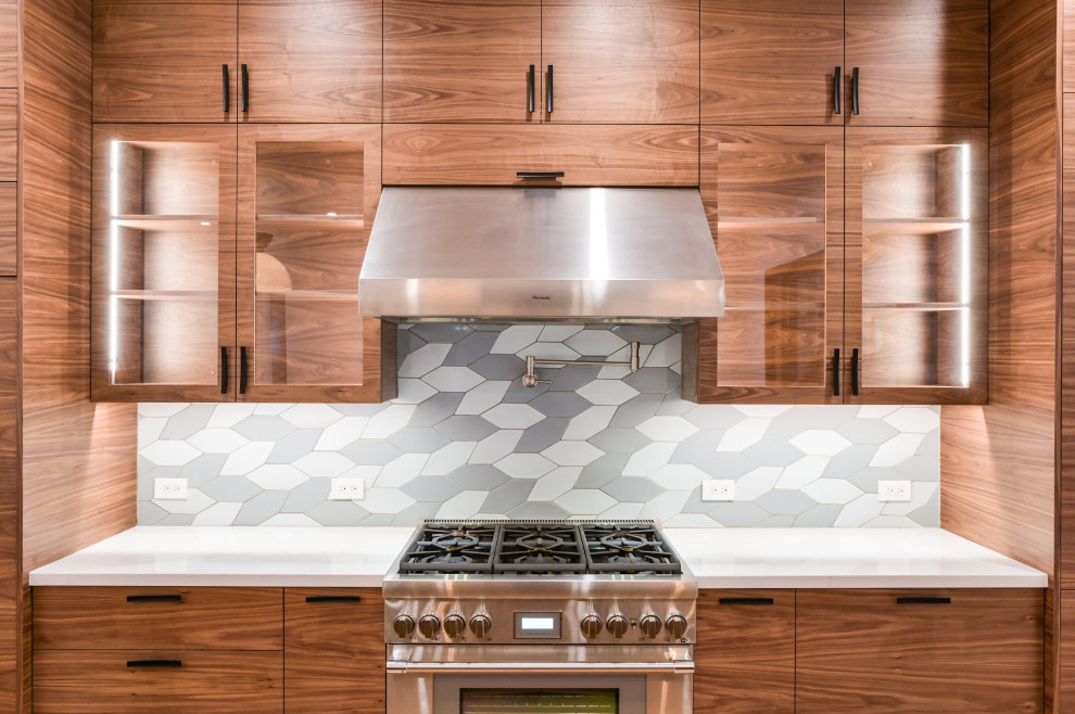 Foto på ett stort funkis vit linjärt kök med öppen planlösning, med en undermonterad diskho, släta luckor, skåp i mellenmörkt trä, bänkskiva i kvarts, grått stänkskydd, stänkskydd i keramik, rostfria vitvaror, ljust trägolv och en köksö
