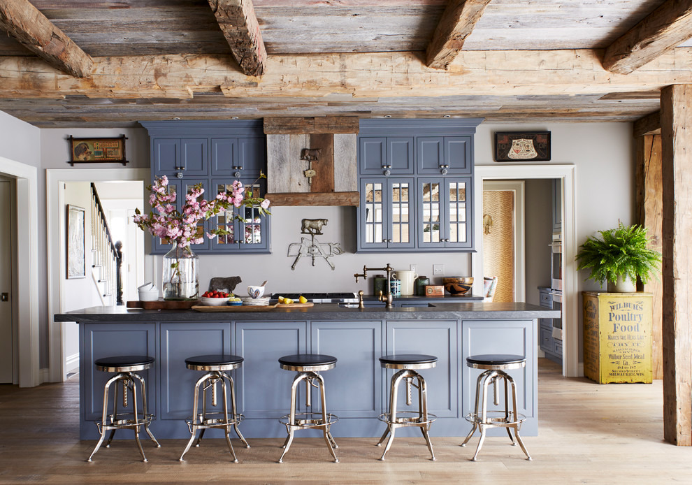 На фото: параллельная кухня в стиле кантри с фасадами в стиле шейкер, синими фасадами, светлым паркетным полом, островом и коричневым полом